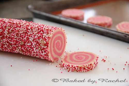 A log of cookie dough with a spiral pattern, coated in sprinkles.